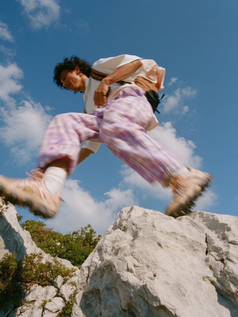 A climber mid-leap between limestone boulders against a blue sky